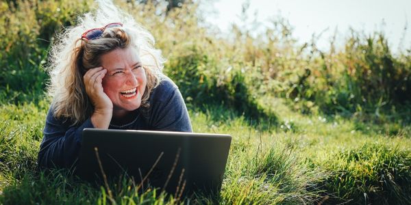 Leben geniessen - Birgit Gosejacob liegt lachend mit Laptop im Gras